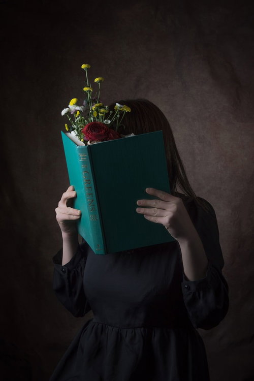 緑色の本で顔を隠す読書女性のポートレート