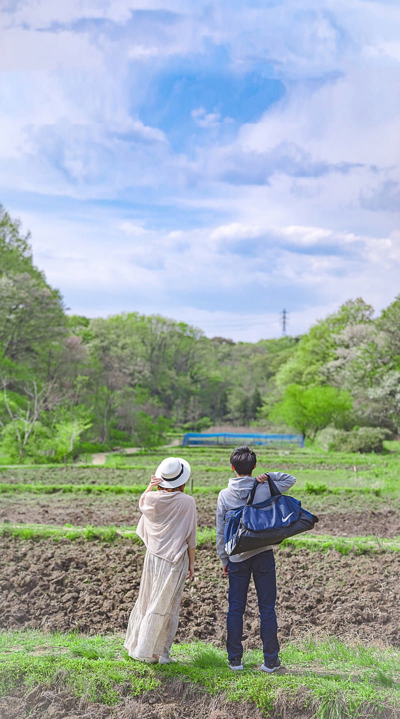 田んぼの前に立つ男女の後ろ姿、青空と緑の田園風景
