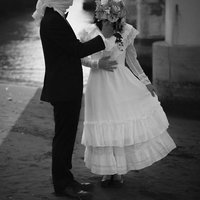 ブーケを掲げる覆面の男性と白いドレスの女性の写真