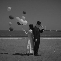 幸せな女性と謎多きともだち：海辺で風船を放つカップルの写真