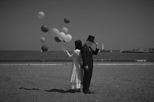 幸せな女性と謎多きともだち：海辺で風船を放つカップル