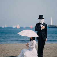 覆面をした男子と白いドレスのお嬢様が砂浜で向き合うの写真