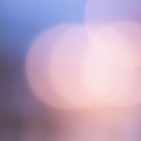 紫とオレンジの丸ボケが重なる光のグラデーションの写真