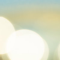 淡いレモン色の光のグラデーションと丸ボケの写真