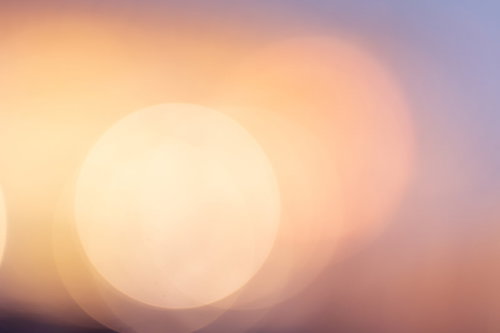 オレンジから淡いピンクへのグラデーションに浮かぶ柔らかな丸ボケ