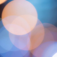 青く冷たい光の中で暖かみのあるオレンジ色の丸ボケの写真