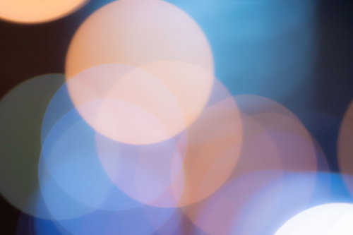 青く冷たい光の中で暖かみのあるオレンジ色の丸ボケ