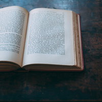 古いテーブルに開かれた洋書の頁の写真