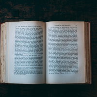 深緑のテーブルに開かれた洋書の古い装丁と活字ページの写真