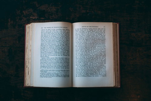 深緑のテーブルに開かれた洋書の古い装丁と活字ページ