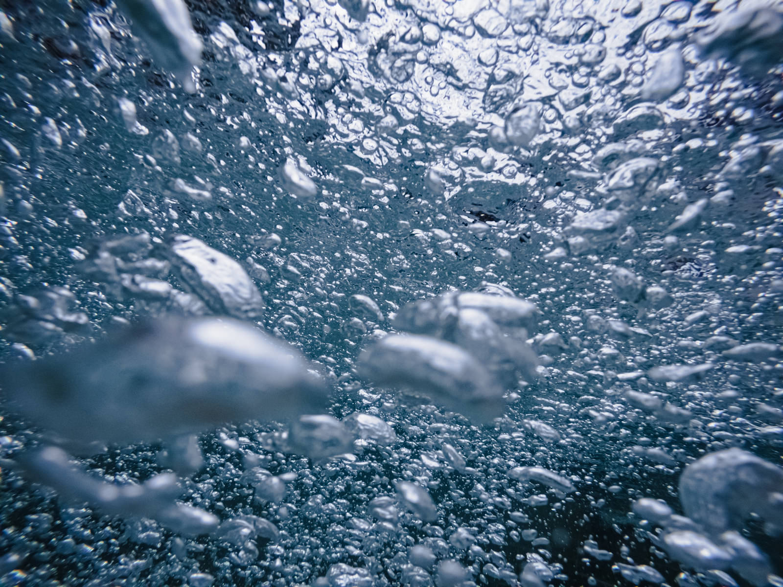 水中で沸き立つ無数の気泡が青い背景に浮かぶテクスチャー