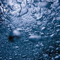 気泡で溢れる水中のテクスチャー 青い水の中で輝く無数の泡の写真