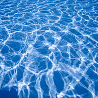 プールの水面に映る光のまだら模様と気泡の写真
