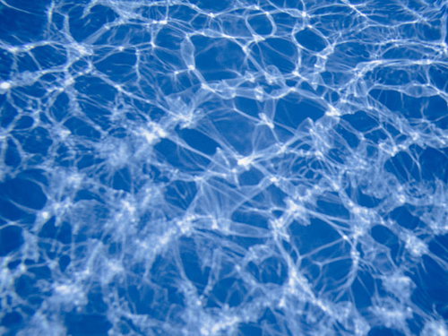 プールの水中に差し込む太陽光の斑模様と気泡