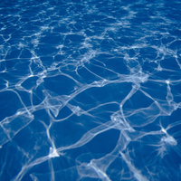 プールの水中を走る光の斑模様と波紋のテクスチャーの写真