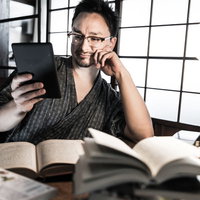 古民家の和室でキンドルをチェックする外国人男性の写真