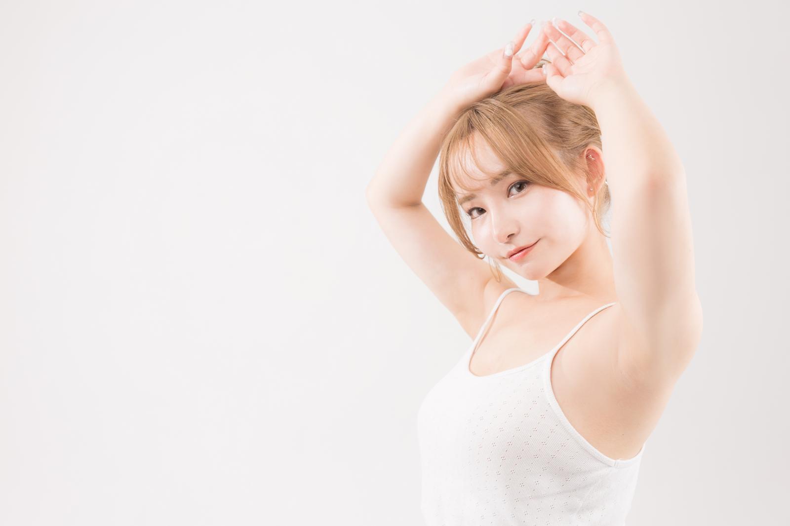 両腕を上げてポーズする白いキャミソール姿の女性［モデル：yuria］