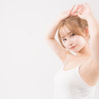 両腕をあげてポーズする美容女子のスキンケアの写真