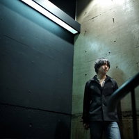 冷たいコンクリートの地面にしゃがみ込んでうつむく男性の写真