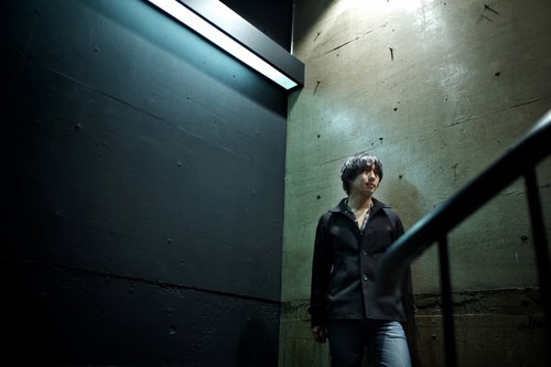 冷たいコンクリートの地面にしゃがみ込んでうつむく男性