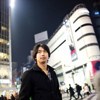 スーツ姿で渋谷のスクランブル交差点の人波の中を歩く男性の写真