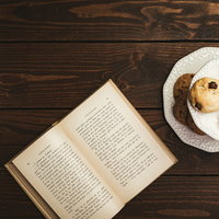 卓上に置かれた読みかけの洋書と白い皿のクッキーの写真