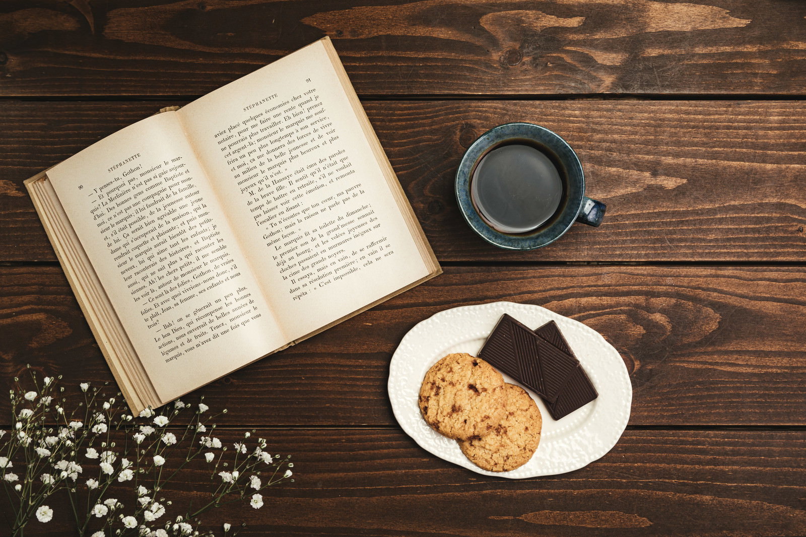 木製テーブルのコーヒーとクッキーと洋書