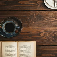 喫茶店のテーブルに置かれた洋書とブラックコーヒーの写真