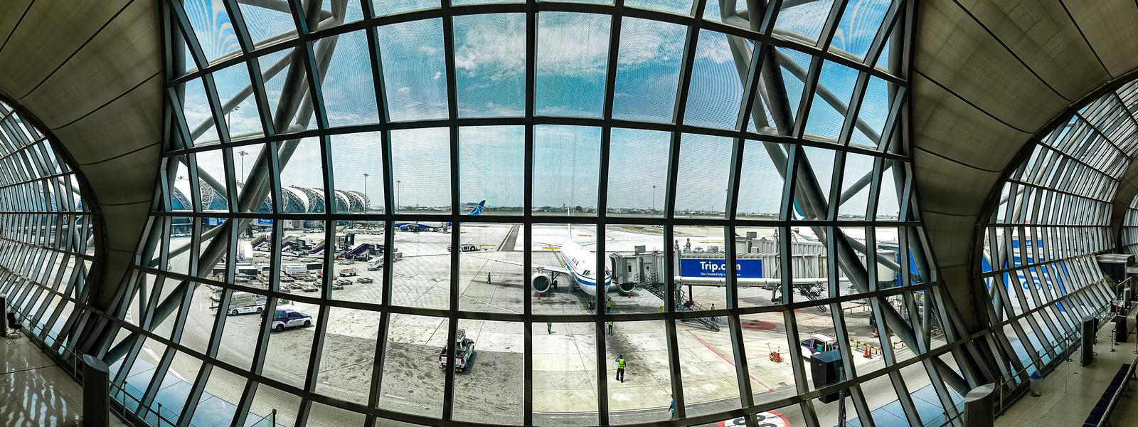 Viewing the runway and aircraft from the curved glass windows of an airport terminal
