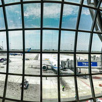 空港ターミナルの大きな窓から見る滑走路と航空機の写真