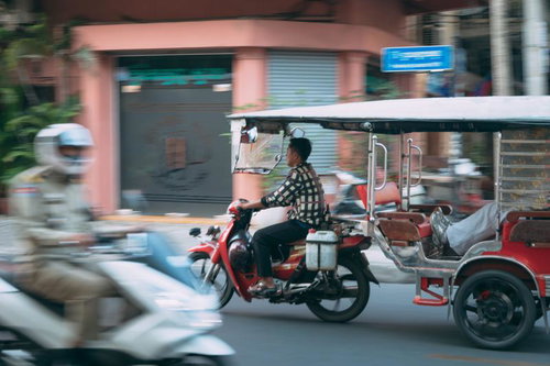 カンボジアの街でバイクとトゥクトゥクが並走する交通風景
