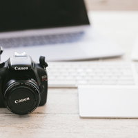 デスクに置かれたパソコンと一眼レフカメラの写真