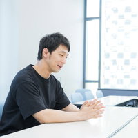 オフィスのデスクで話すろくろ回しの男性の写真