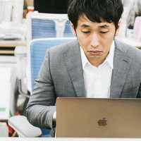 突然のパソコンフリーズに表情が固まる男性の写真