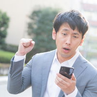 テレビ電話でスマホを見て怒る敏腕編集者の男性の写真
