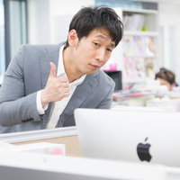 デザインカンプを褒めるウェブディレクター、OKサインを出す男性の写真