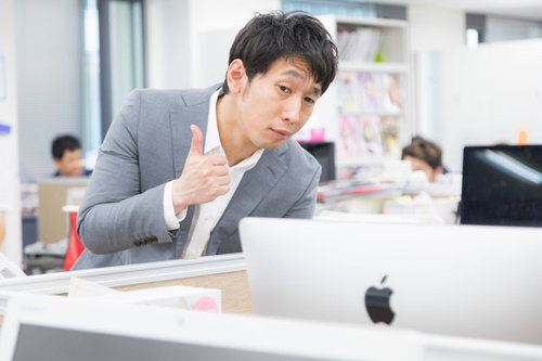 デザインカンプを褒めるウェブディレクター、OKサインを出す男性