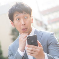 スマートフォンのマッチング通知に驚く独身男性の写真