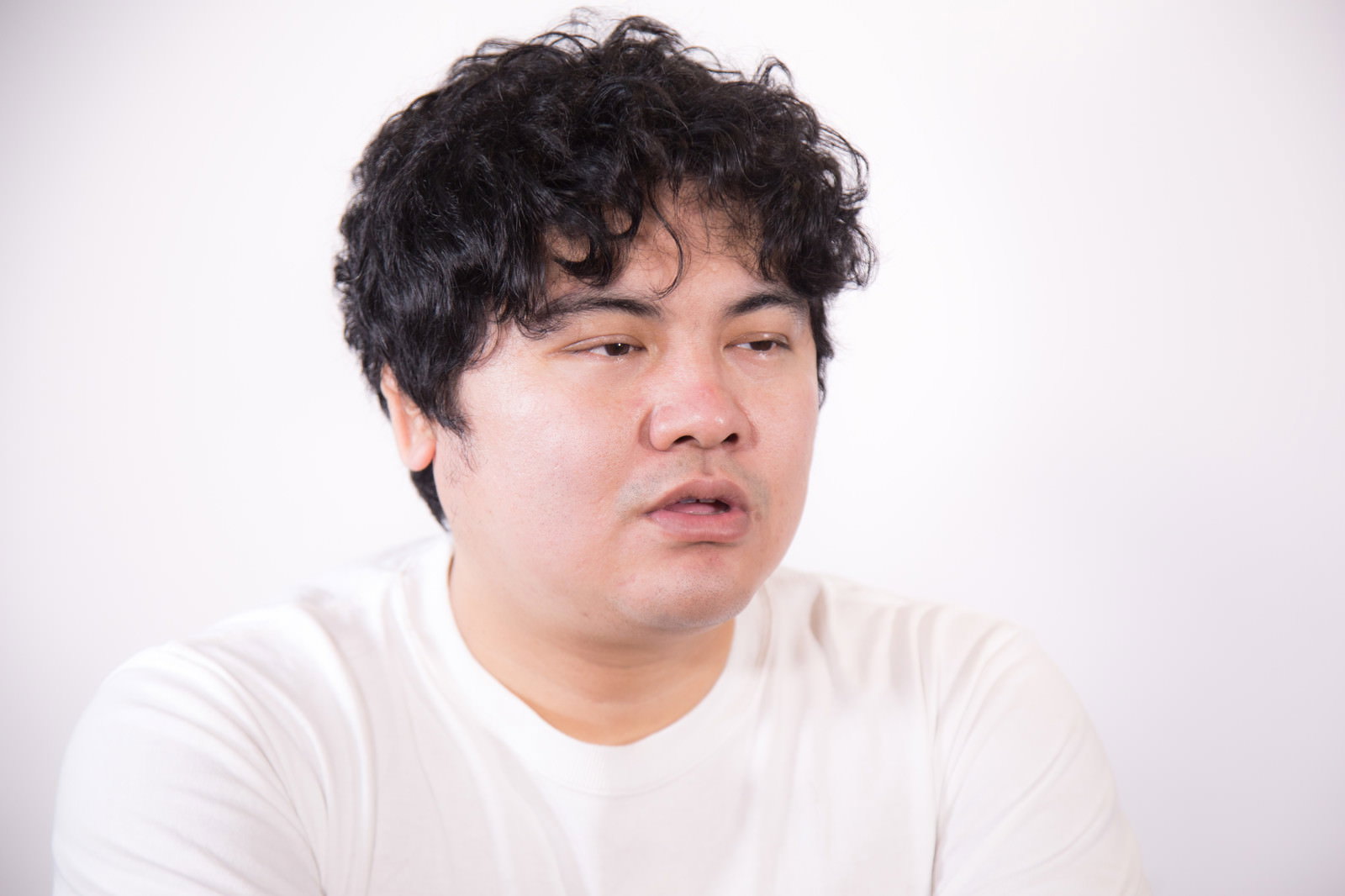 白いTシャツを着た男性が怒りの表情を浮かべている［モデル：段田隼人］