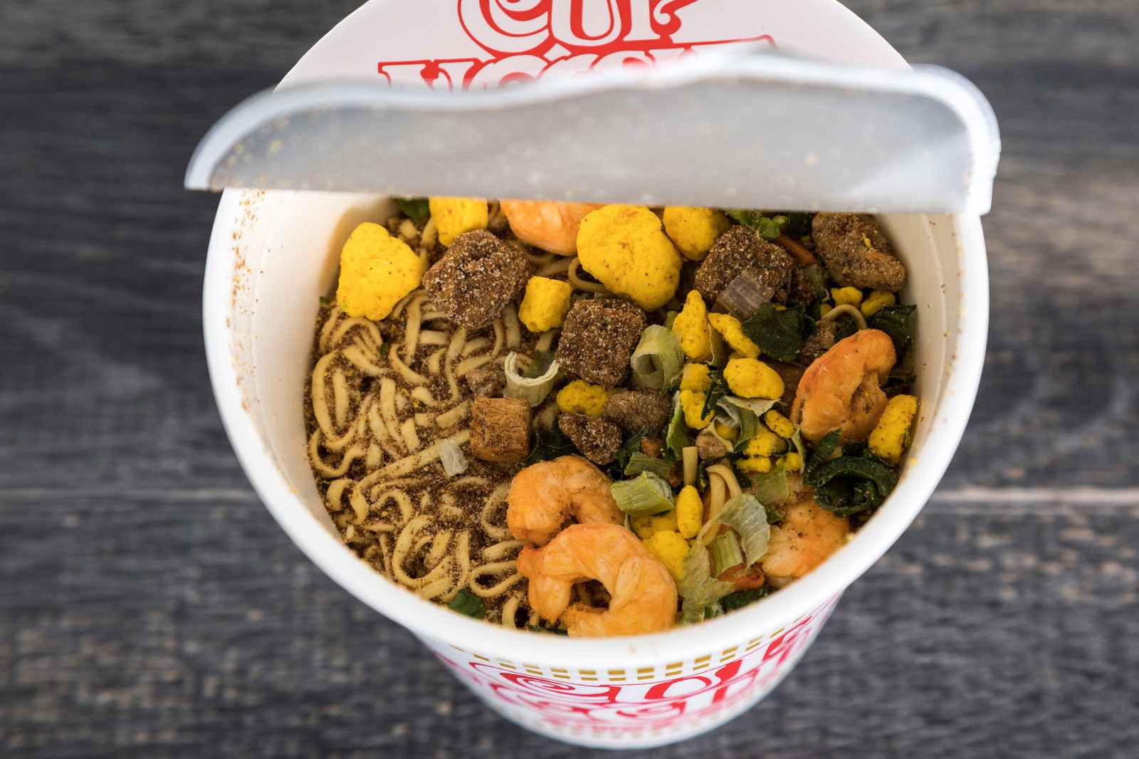 白いカップ容器に入った乾燥麺と具材が見えるカップラーメン