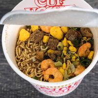 お湯を入れる前のカップ麺、乾燥した麺と具材が見える状態の写真