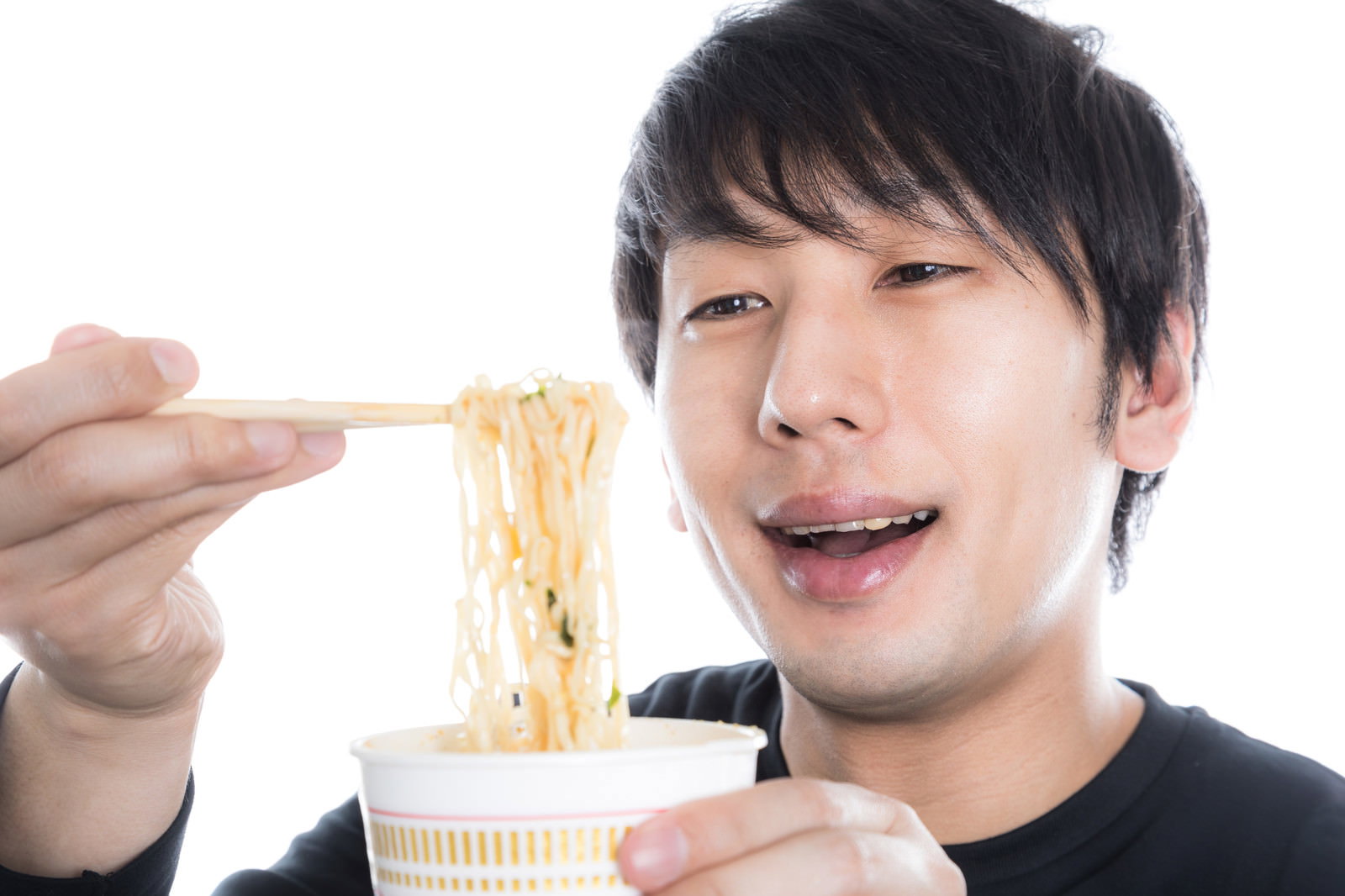 Man smiling and eating cup ramen with chopsticks