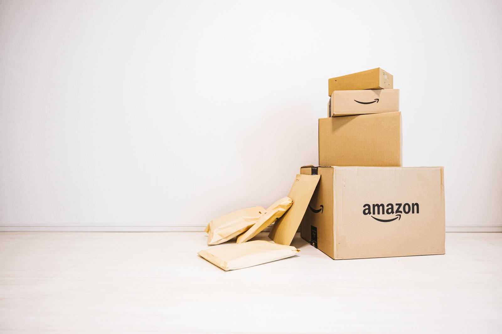 amazonのロゴが入った段ボール箱に他の箱が積み重なり、梱包材がはみ出ている