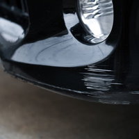 縁石で擦ってしまった黒い車のフロントバンパーの写真