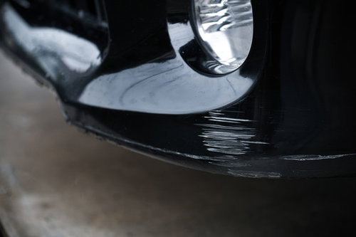 縁石で擦ってしまった黒い車のフロントバンパー