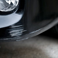 バンパーを擦って大きな傷がついてしまった白い自動車の写真