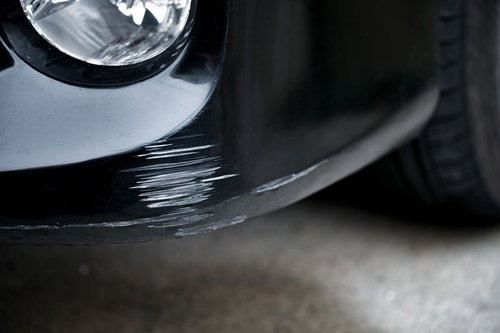 バンパーを擦って大きな傷がついてしまった白い自動車