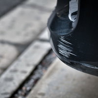 黒い車のバンパーを傷つけてしまった事故後の状況の写真