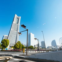 横浜みなとみらいでランドマークタワーを一望しながらオープンカーで走行中の写真
