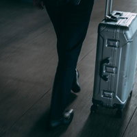 空港でスーツケースを運ぶ旅行者の足元と荷物の写真